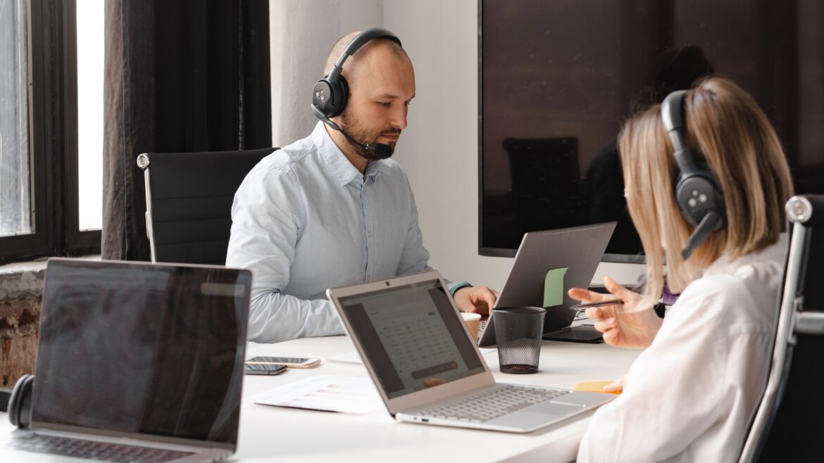 two person on a laptop with headset working